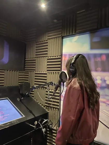 Sarea recording in her studio, wearing headphones at a microphone, surrounded by acoustic foam